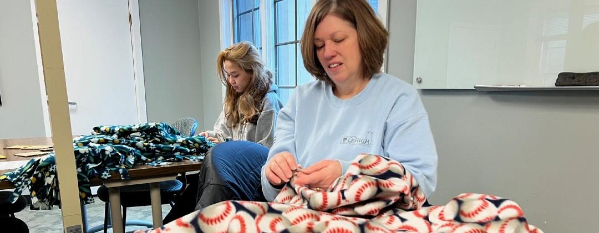 Carol Hill, director of Student Center Facilities, makes a no-sew blanket for Project Linus during the MLK National Day of Service. Project Linus makes new blankets for children experiencing hardship or trauma. Shown in the background is Ujin Khongorzul '26. Photo: Christina Tatu