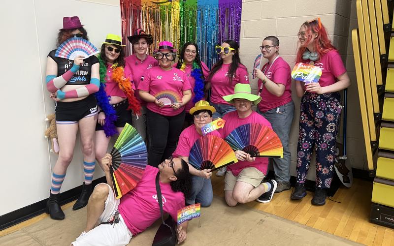 Pride Center Student Staff and Professional staff at pride a palooza with colorful background decorations and phot booth props